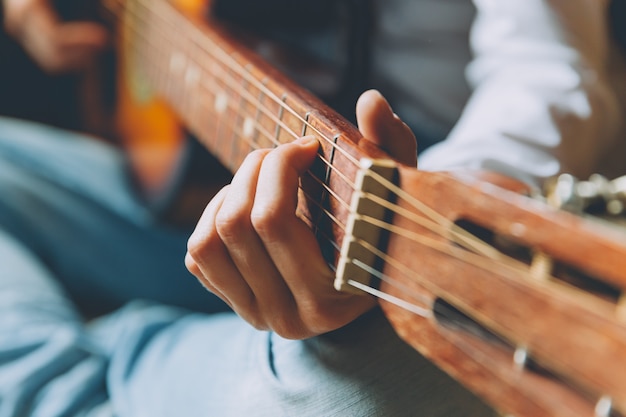 Resta a casa Resta al sicuro. La giovane donna che si siede a casa e che gioca la chitarra, mani si chiudono su. Ragazza teenager che impara suonare e scrivere musica. Lo stile di vita hobby si distende Concetto di educazione del tempo libero dello strumento.