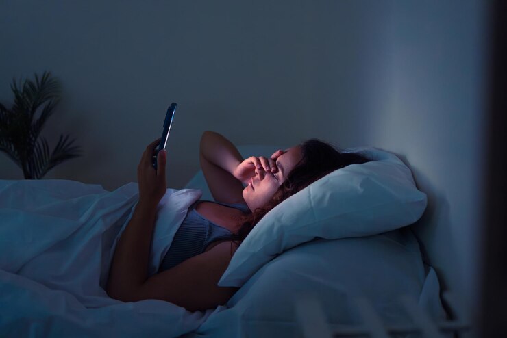 Restless in bed young woman gripped by insomnia seeks solace in her smartphones gentle radiance