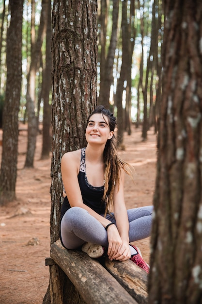 Resto sportivo della donna che si siede sugli alberi giù