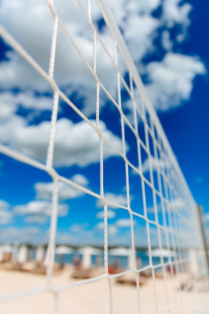 Rete bianca per pallavolo situata sulla spiaggia di sabbia vicino al lago. Bel tempo estivo e cielo blu. Attività all'aperto durante i fine settimana.