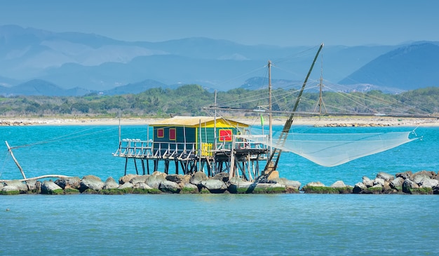 Rete da pesca tipica e casa del pescatore con sopra il mare a Marina di Pisa, Toscana, Italia