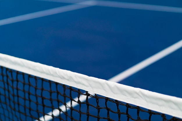 Rete diagonale di tennis con la banda bianca nel campo da tennis in terra battuta blu, concetto della concorrenza di tennis