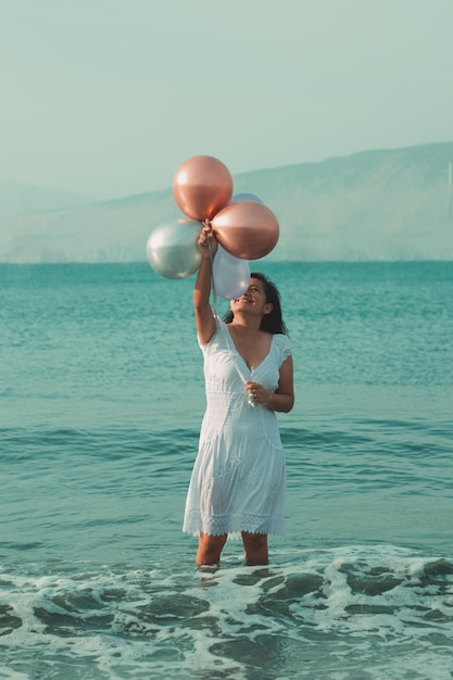 Retrato de una chica en la playa con globos