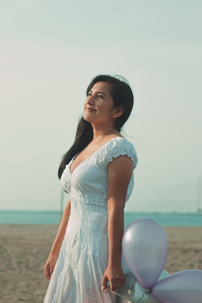 Retrato de una chica en la playa con globos