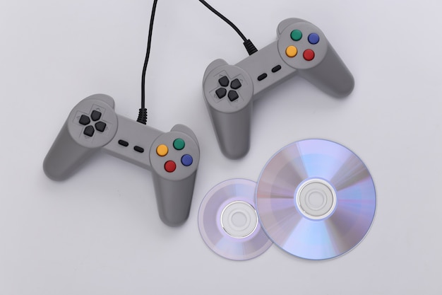 Retro gamepad e CD su sfondo bianco. Gioco, competizione di videogiochi. Vista dall'alto