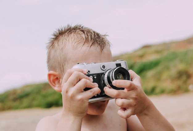 Retro spiaggia della macchina fotografica del ragazzino che prende le immagini