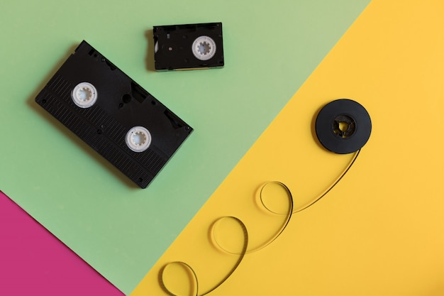 Retro videocassetta e film su uno sfondo di carta pastello a tre colori.