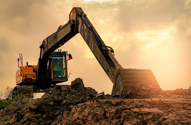 Retroescavatore parcheggiato in cantiere dopo aver scavato il terreno Bulldozer sul cielo al tramonto e nuvole backgroud