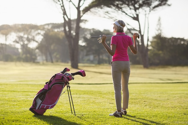 Retrovisione del club di golf maturo della tenuta della donna