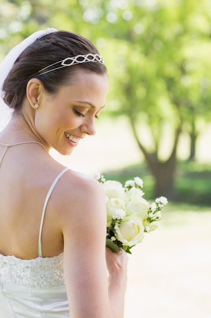 Retrovisione della sposa timida con i fiori in giardino