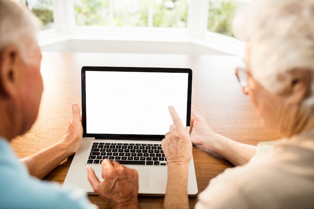 Retrovisione delle coppie senior facendo uso del computer portatile a casa