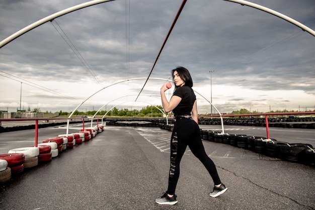 Retrovisione di giovane ragazza atletica che fa gli esercizi con le teste di legno sul campo da giuoco all'aperto dopo la quarantena COVID-19. Assistenza sanitaria, concetto di sport