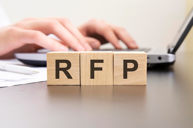 Rfp acronimo da blocchi di legno con lettere sfondo mani su un computer portatile con sfocatura del concetto di business