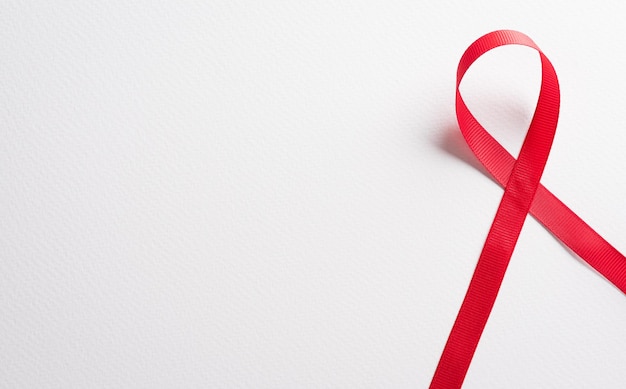 Ribbon rosso di primo piano Ribbon di consapevolezza per la Giornata Mondiale dell'AIDS HIV su sfondo bianco Concetto di assistenza sanitaria e medicina