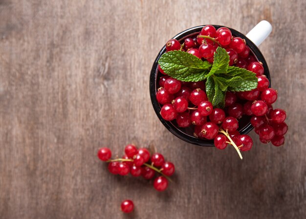 Ribes fresco con la menta in tazza su fondo di legno marrone