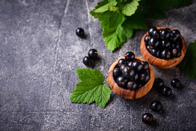 Ribes nero con foglie in ciotole di legno