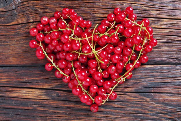 Ribes rosso a forma di cuore sulla vista superiore del fondo di legno