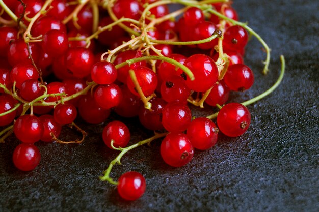 Ribes rosso in una ciotola bianca sul tavolo nero.