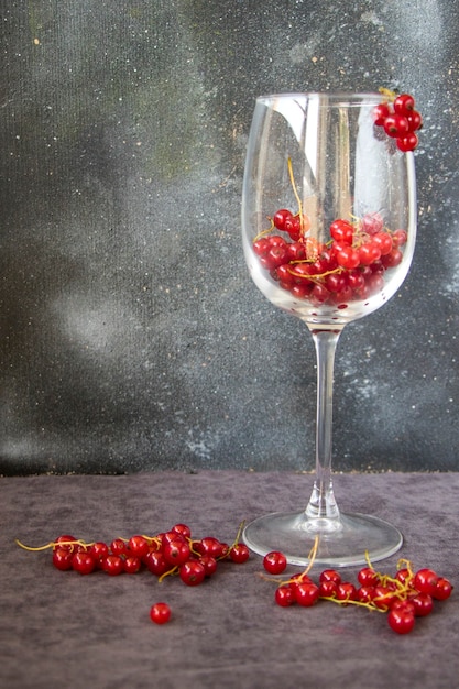 Ribes rosso nel bicchiere di vino sullo sfondo grigio e blu. Grande gruppo di bacche colorate.