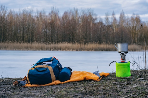 Ricarica il tuo smartphone mentre viaggi con un power bank. Un caricabatterie portatile carica il telefono sullo sfondo di un bruciatore a gas turistico e una foresta.