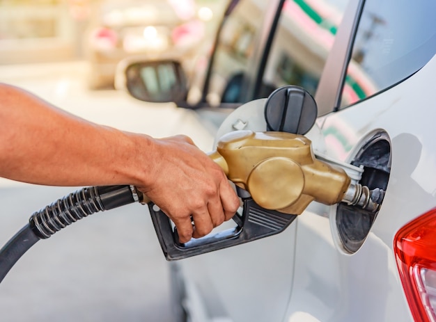 Ricarica la macchina a mano con il carburante alla stazione di benzina