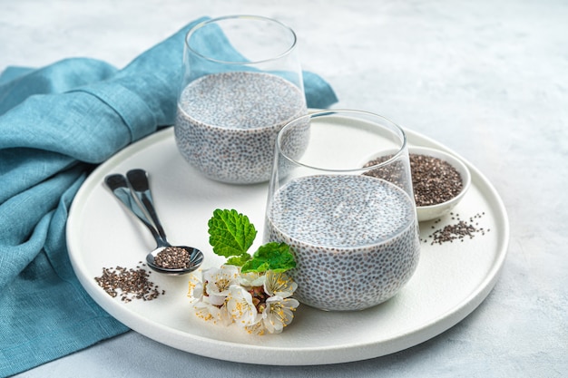 Ricco di vitamine, calcio e omega 3 dessert con semi di chia e latte di cocco su una parete grigia. Vista laterale, primo piano.