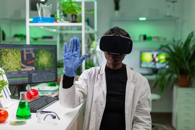 ricercatore biologo africano con cuffie per realtà virtuale alla ricerca di un nuovo esperimento genetico