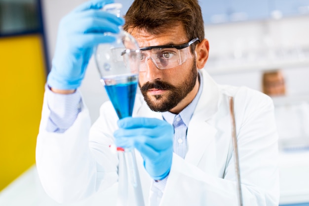 Ricercatore che lavora con liquido blu all'imbuto separatore in laboratorio