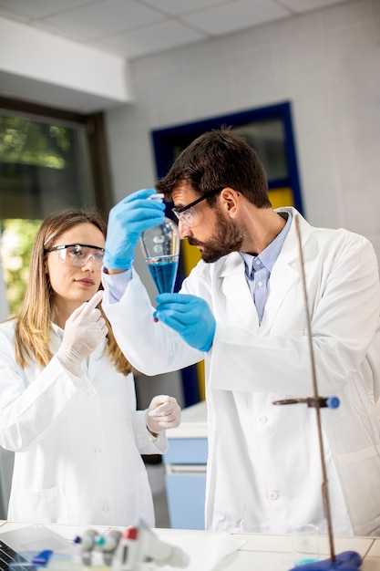 Ricercatore che lavora con liquido blu all'imbuto separatore in laboratorio