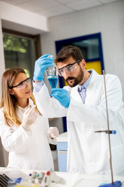 Ricercatore che lavora con liquido blu all'imbuto separatore in laboratorio