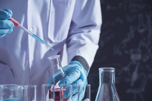 Ricercatore con provette chimiche da laboratorio in vetro con liquido per ricerca analitica, medica, farmaceutica e scientifica.
