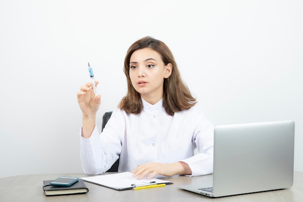 Ricercatore di laboratorio femminile che tiene la siringa con liquido blu. Foto di alta qualità