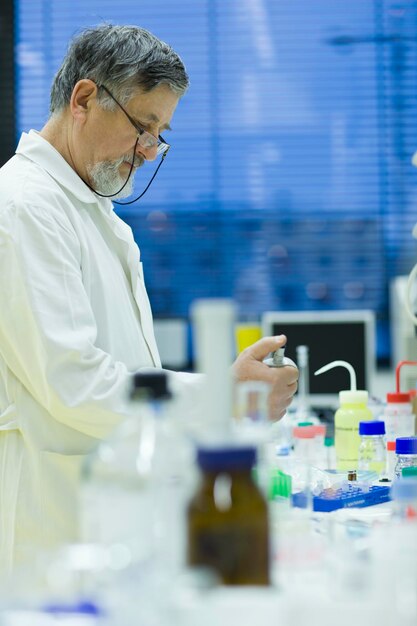 Ricercatore maschio senior che svolge ricerche scientifiche in un laboratorio utilizzando un'immagine a colori DOF poco profonda con gascromatografo