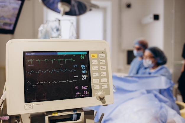 Ricercatore medico che esamina l'immagine ECG mostrata sul monitor mentre patinet con maschera in esecuzione su cross trainer che testa la frequenza cardiaca utilizzando elettrodi