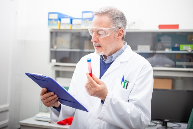 Ricercatore medico sientista guardando una provetta di sangue, esame del sangue di coronavirus