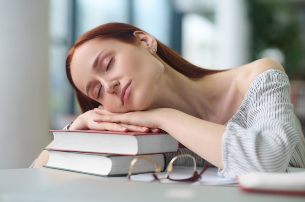 Ricercatore oberato di lavoro che fa un pisolino in una biblioteca pubblica