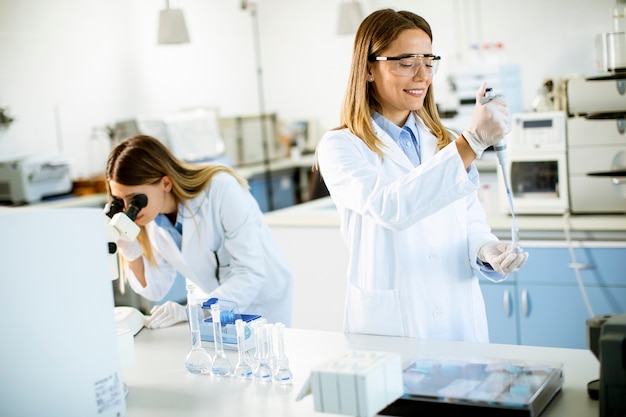 Ricercatrici sveglie in camice bianco che lavorano in laboratorio