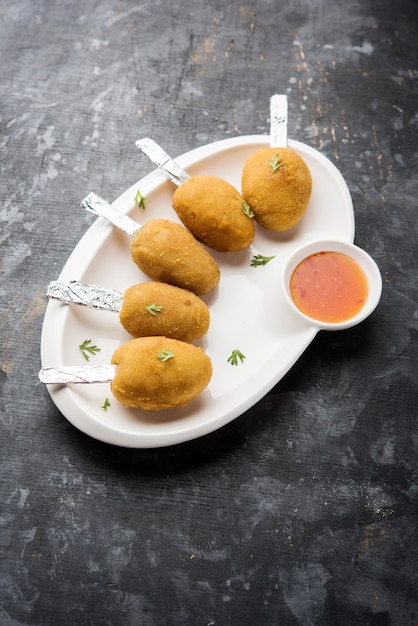 Ricetta del lecca-lecca croccante Veg a base di patate bollite con spezie ricoperte di farina di mais e pangrattato e poi fritte, servite con stuzzicadenti o stecco di gelato