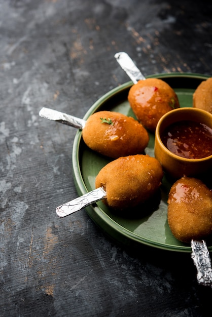 Ricetta del lecca-lecca croccante Veg a base di patate bollite con spezie ricoperte di farina di mais e pangrattato e poi fritte, servite con stuzzicadenti o stecco di gelato