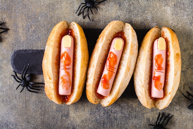 Ricetta di Halloween hot dog con dita di salsiccia in ketchup su un'ardesia sul tavolo Vista dall'alto Primo piano