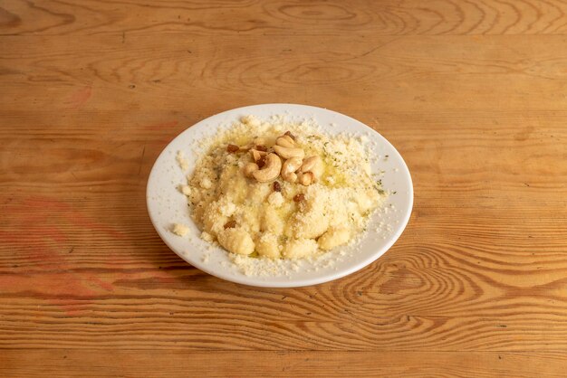 Ricetta italiana degli gnocchi con formaggio grattugiato e frutta secca anacardi arachidi e uvetta con origano