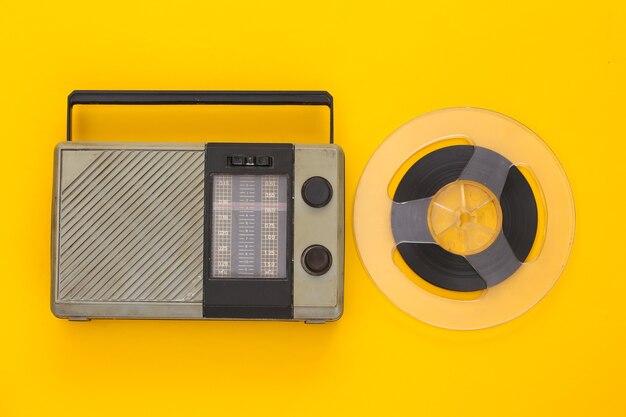 Ricevitore radio portatile retrò e bobina di nastro magnetico audio su giallo