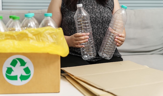 Riciclaggio domestico eco green zero concept Donna che lancia una bottiglia di plastica vuota nel contenitore per il riciclaggio con sacchi per rifiuti gialli a casa