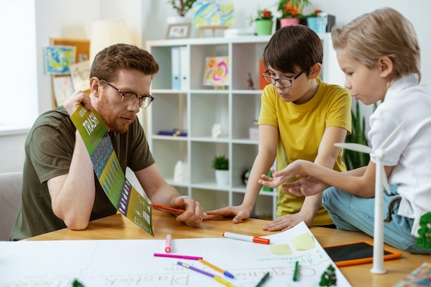 Riciclaggio per l'ambiente. Attento uomo intelligente che indica gli elementi sul poster educativo e li discute