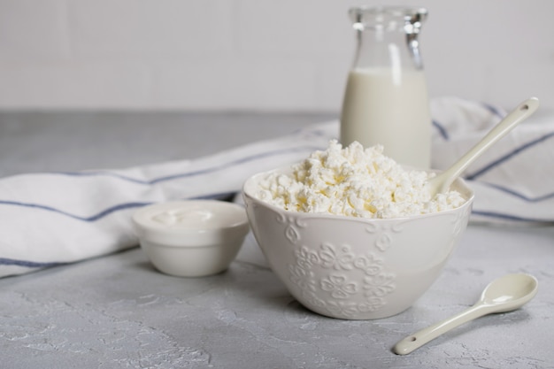 Ricotta biologica, cagliata in una ciotola di ceramica bianca, panna acida e latte in bottiglia