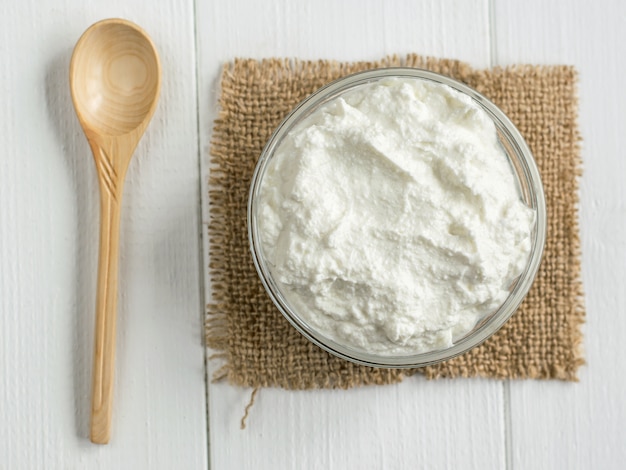 Ricotta e cucchiaio appena fatti sulla tavola di legno bianca.