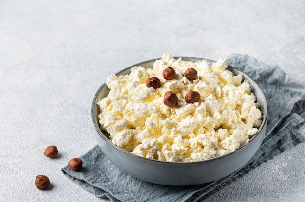 Ricotta e nocciola in una ciotola grigia su sfondo bianco. Colazione salutare. Concetto di cibo sano.