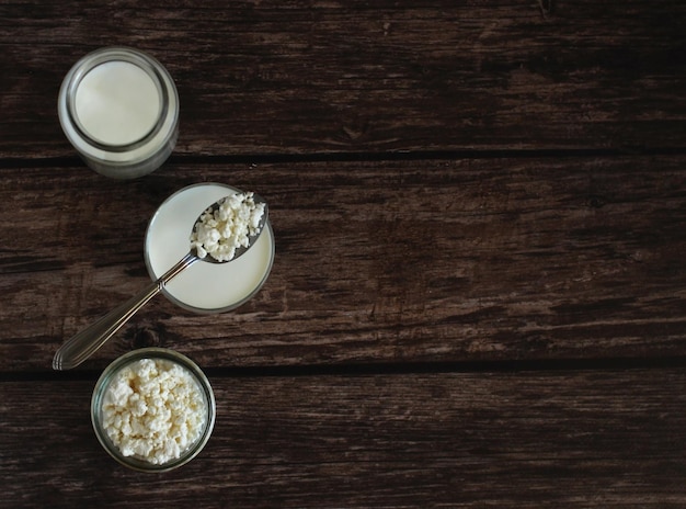 Ricotta fatta in casa con kefir in un bicchiere di vetro con un cucchiaio su uno sfondo di legno