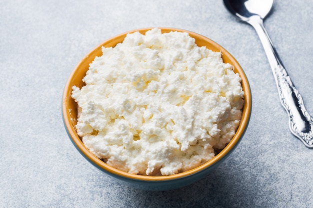 Ricotta fatta in casa in una ciotola in ceramica su un tavolo grigio.