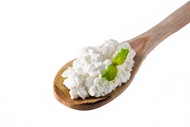 Ricotta fresca in un cucchiaio di legno isolato su bianco